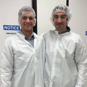 Amylyx co-CEOs Justin Klee and Josh Cohen posing together in labcoats.